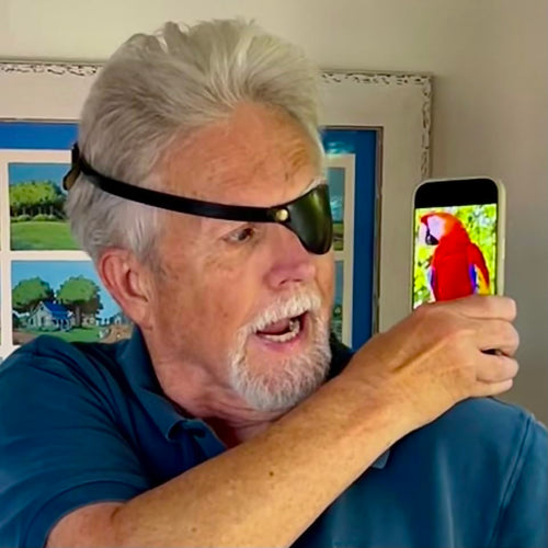 Man holding a smartphone with a parrot image, wearing a black eye patch.