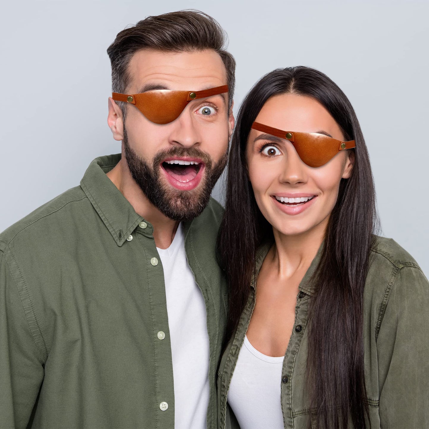 Two people wearing brown eye patches with a surprised expression on a light gray background