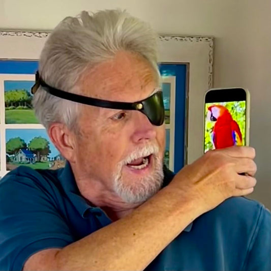 Man holding a smartphone with a parrot image, wearing a black eye patch.
